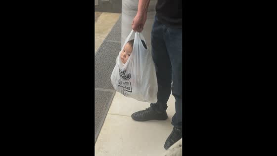 Man carries toddler in plastic bag during rain in Yunnan, China