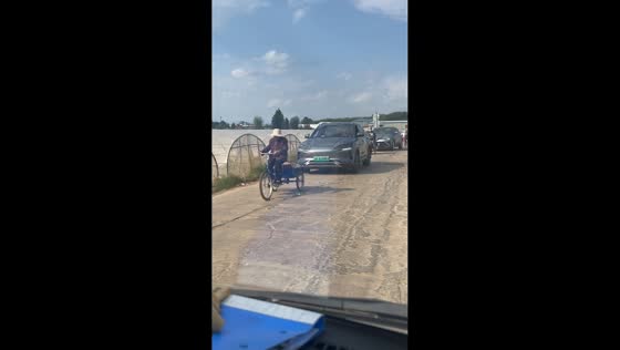 Elderly rider slowly drives cargo tricycle as vehicles wait behind in Yunnan, China