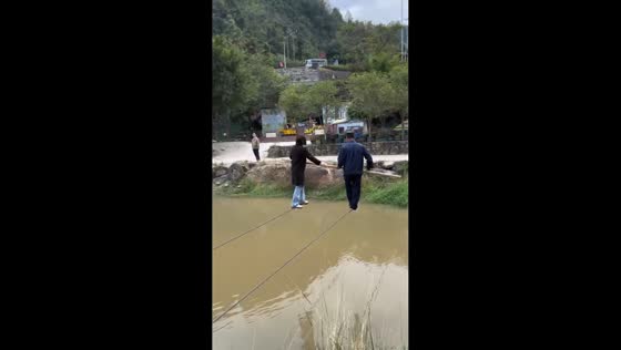 Woman and staff cross river on tightrope in Jiangxi, China