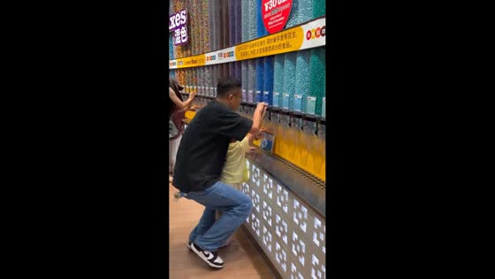 Father and son overfilling MandMs container in Shanghai, China 