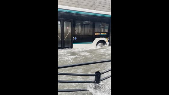 Bus creates waves while traveling through a flooded road in Shanghai, China