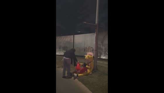 Woman helps mascot and child on roadside in Tangerang, Indonesia