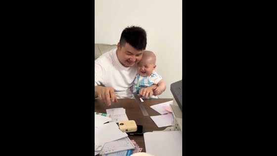 Father makes baby laugh by ripping paper with ruler in Guangdong, China