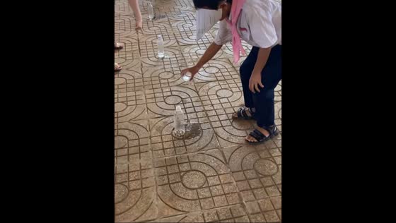 Blindfolded boy misses bottle while pouring water in Mang Den, Kon Tum Province, Vietnam