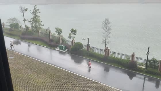 Child swept by wind and rain chases after man in Hunan, China