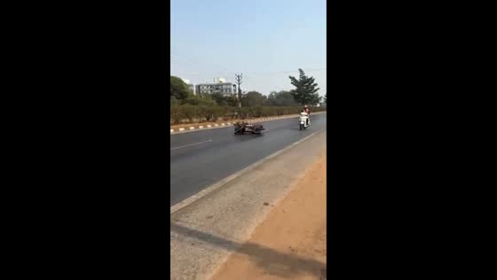 Motorcyclists slip on oil-slicked road in Raipur, India
