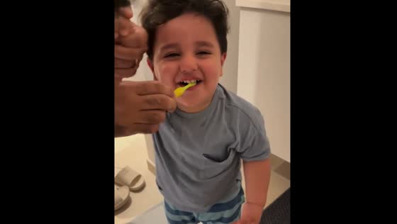Child giggling while brushing teeth in Denmark