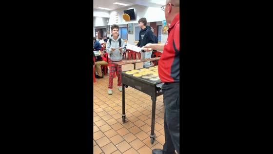 School worker flips pancakes through the air into students’ plates in St. Louis, Missouri, USA