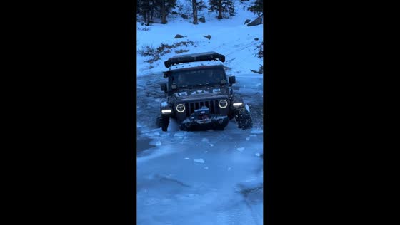 Jeep crosses frozen river after ice breaks in Nordegg, Alberta, Canada