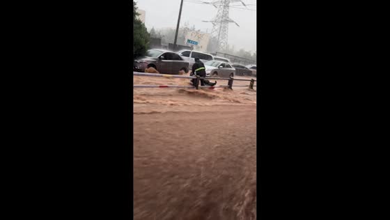 Floodwaters sweep trash bin and push electric bike through roadway in Shandong, China