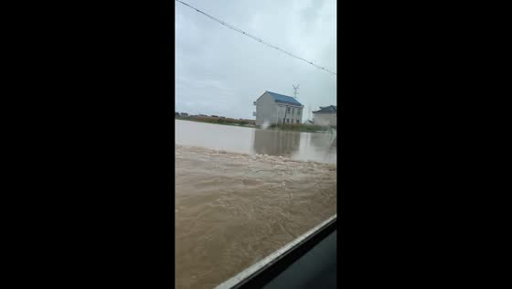 Car drives through murky floodwaters covering residential road in Jiangsu, China