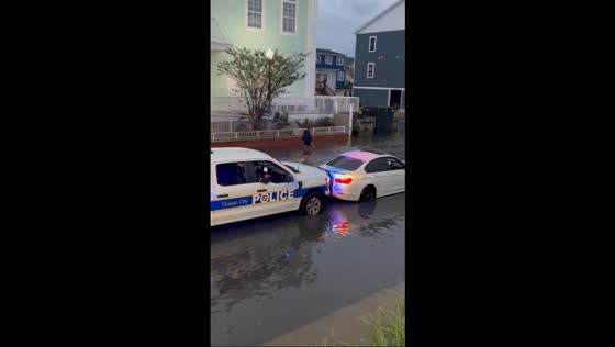 Police car push stalled car out of floodwaters in Ocean City, Maryland, USA