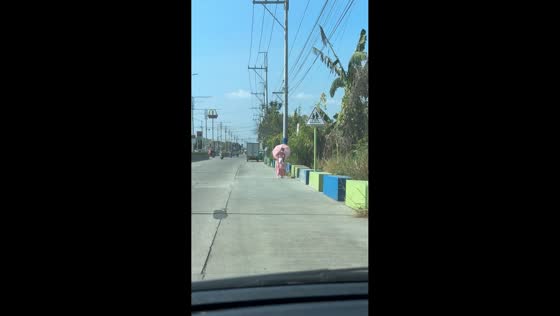 Woman dressed in pink walks under sunny skies in Imus, Philippines