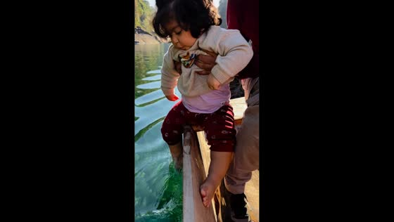 Toddler enjoys playing in Umngot River while on boat in Meghalaya, India