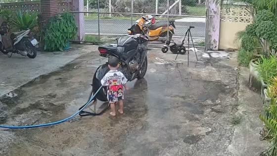 Kid inserts hose into motorcycle exhaust in Chiang Rai, Thailand