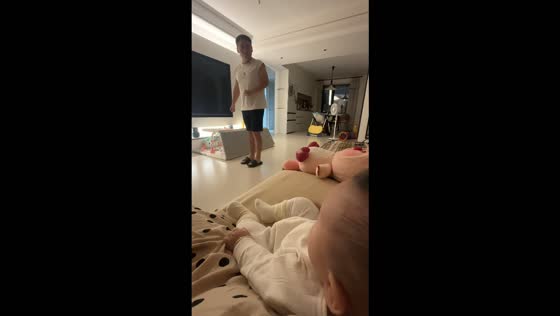 Man accidentally kicks his slippers toward a woman while entertaining a baby in Shandong, China