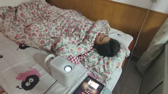 Girl watches TV series projected on ceiling in Beijing, China