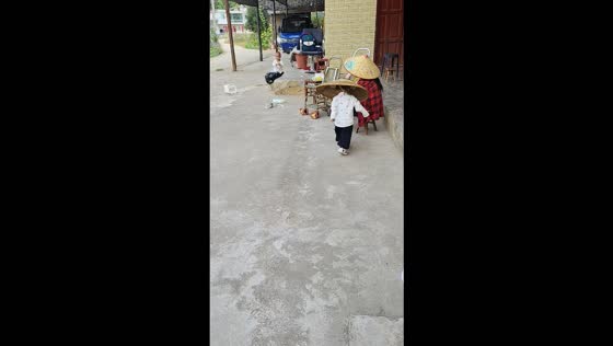Little boy wearing an oversized bamboo hat bumps into an elderly person in Guizhou, China