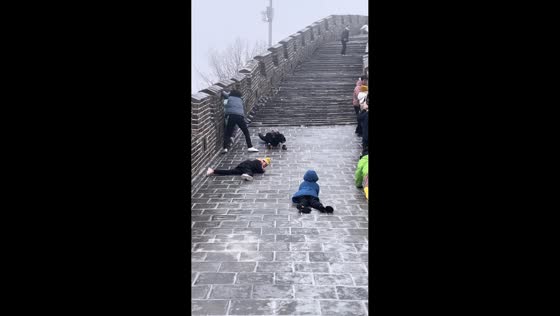 Tourists and children slide on snowy Great Wall steps in Beijing, China