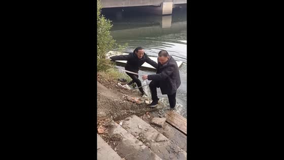 Man slips and falls into the water while riding a wooden board in Anhui, China