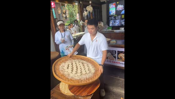 Street vendor skillfully spins tray of sesame pastries in Jiangxi, China