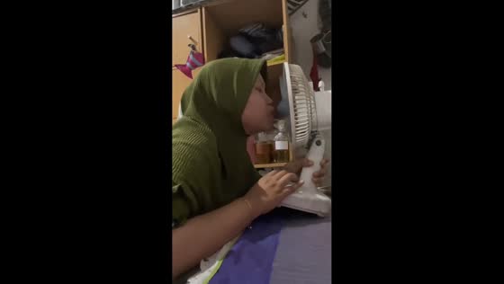 Woman attempts funny trick with mini fan in Surabaya, Indonesia
