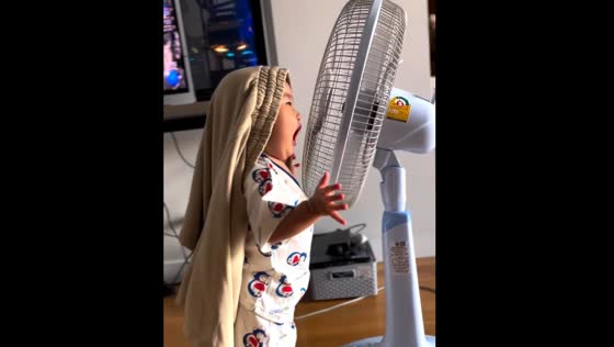 Child interacts with running fan in Bangkok, Thailand