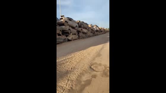 Abandoned cars covered in mud lined up on a street in Catarroja, Spain