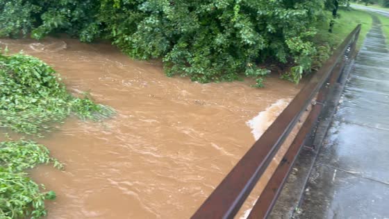 Swollen creek rushes beneath bridge after heavy rainfall in Alabama, USA