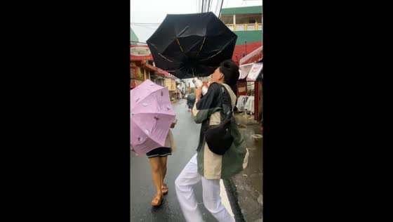 Strong winds challenge people with umbrellas in Lucban, Philippines