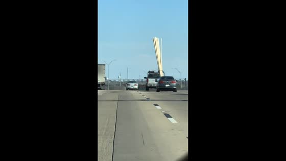 Pickup truck transports lumber vertically on highway in San Antonio, Texas, USA