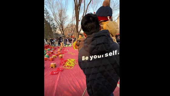 Child throws hoop perfectly onto man's shoulders in Beijing