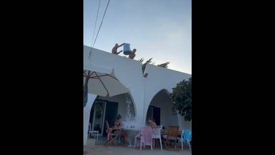People drenched with water while dining outside in San Foca, Italy