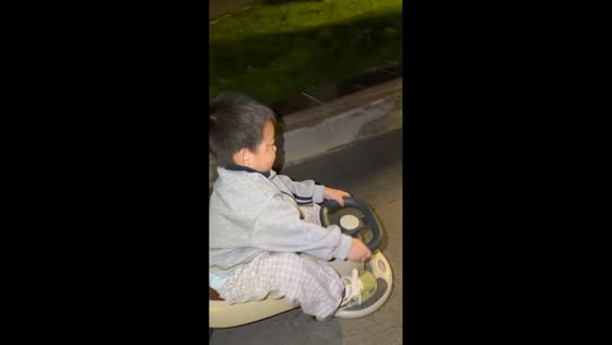 Playful boy lies down while riding twist car in Hebei, China