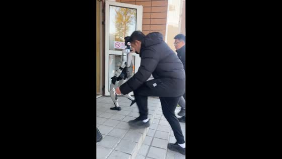 Man helps humanoid robot climb stairs, slips in China