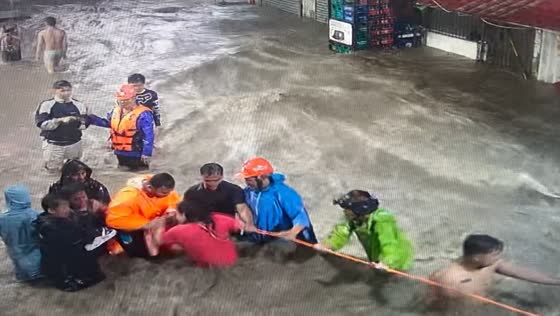 Residents in Biñan use rope to escape floods during storm Kristine