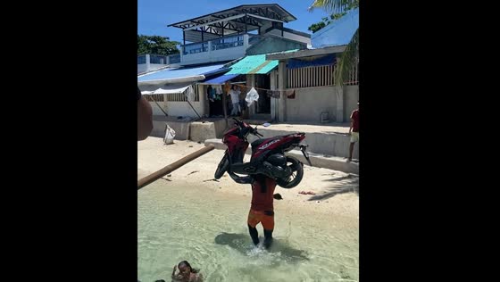 Person carries motorbike on shoulders from boat in Philippines