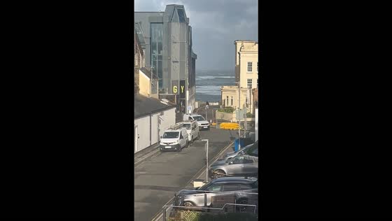 Man struggles to walk against strong winds during a coastal storm in Cornwall, UK