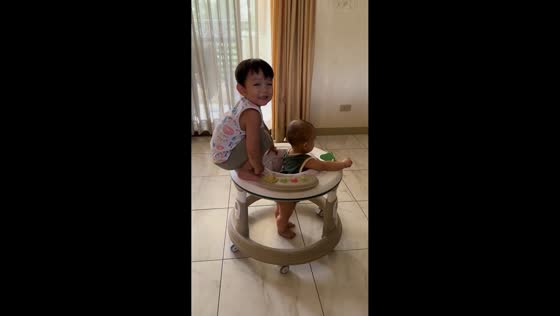 Children playfully share a baby walker in Davao City, Philippines