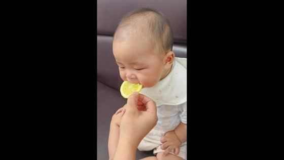 Baby makes funny faces while trying lemon for the first time in Shanghai, China