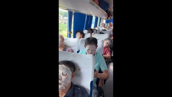 Tour group relaxes on bus with face masks during sightseeing trip in Guangxi, China