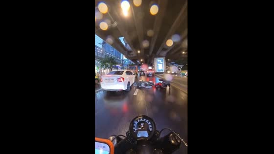 Motorcyclist falls on slippery road in Bangkok during rain