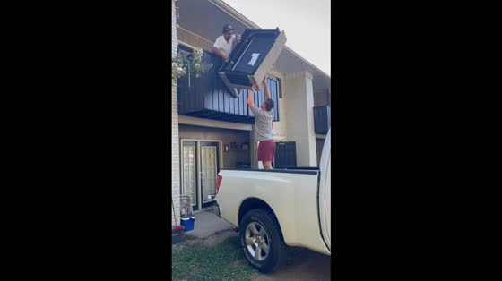 Man lifts couch over balcony in Nashville, Tennessee, USA