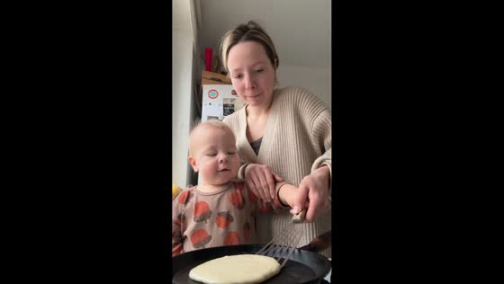 Toddler excitedly flips pancake while cooking breakfast in Moscow, Russia