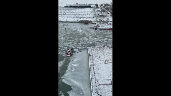 Icebreaker boat pushes through frozen Chicago River near Navy Pier in Chicago, Illinois, USA