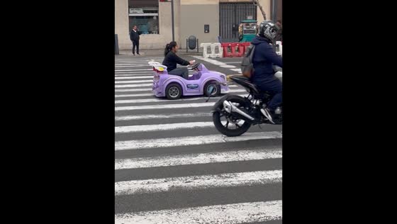 Woman drives child-sized electric car on busy highway in Lima, Peru