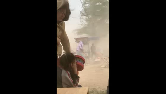 Dust storm reduces visibility as man shields child in Jinan, Shandong, China