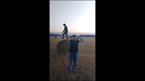 Man poses as friend walks backward on hay bale in Aberdeenshire, Scotland, UK