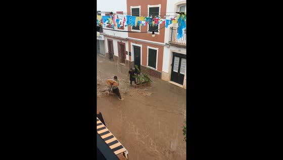 Two people rescue table and plant from flood waters in Es Mercadal, Menorca