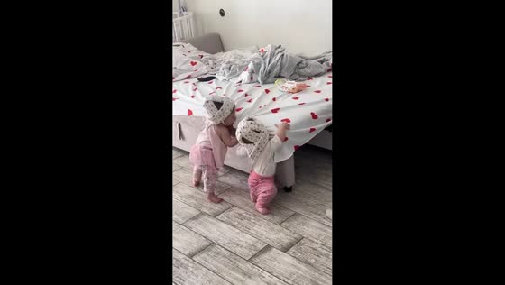 Twin babies playfully tussle with helmets in Simferopol, Russia